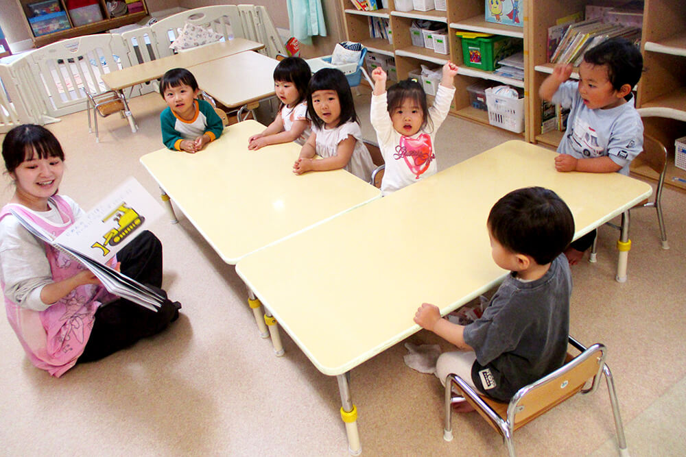 読み聞かせ中の先生と園児たち
